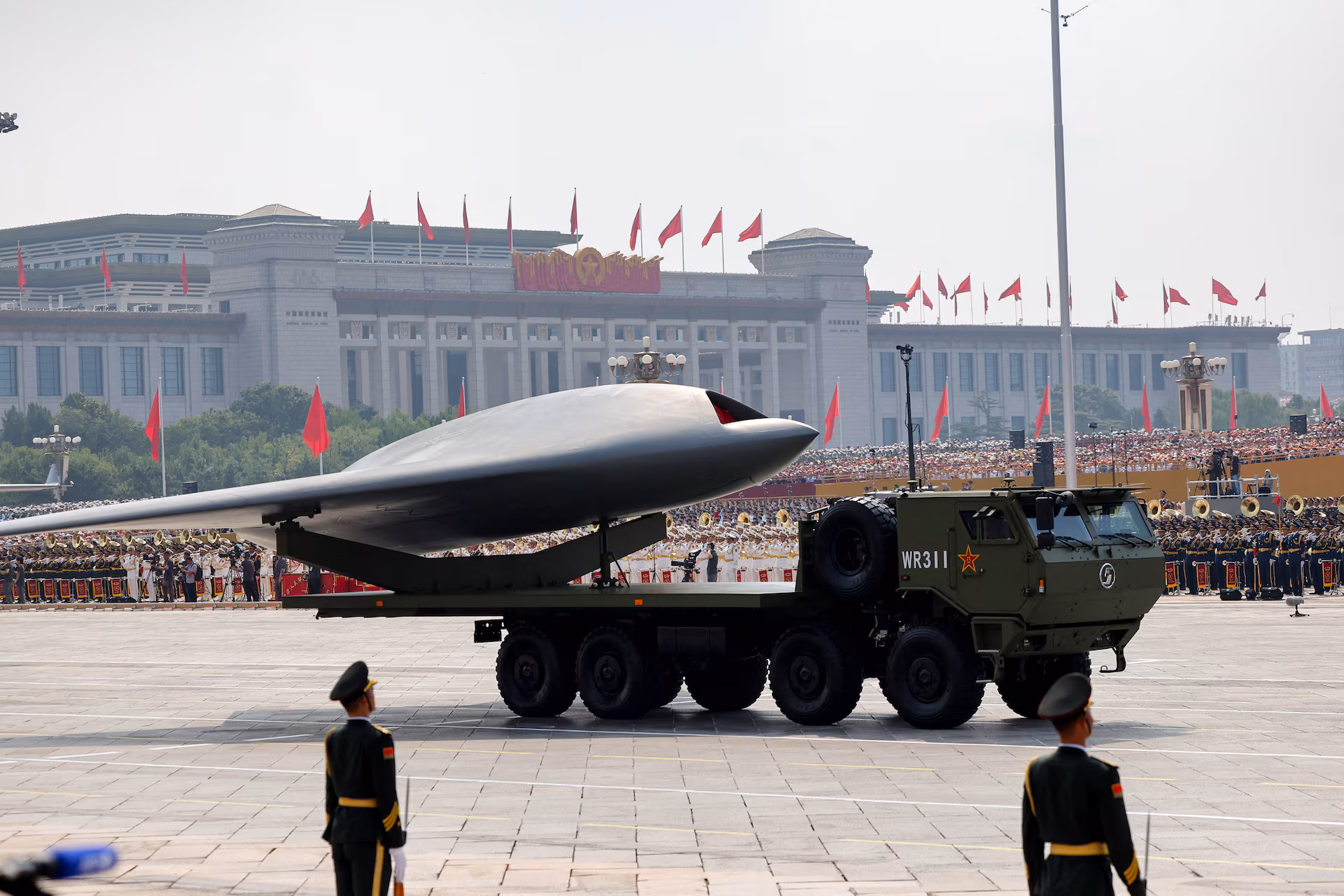 Membros do Exército de Libertação Popular em pé enquanto um veículo aéreo não tripulado é exibido.