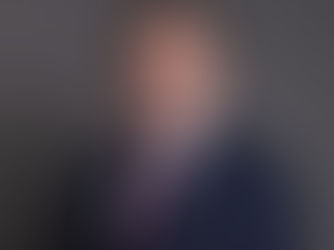 Andy Burnham em foto oficial usando terno escuro, gravata vinho e óculos.