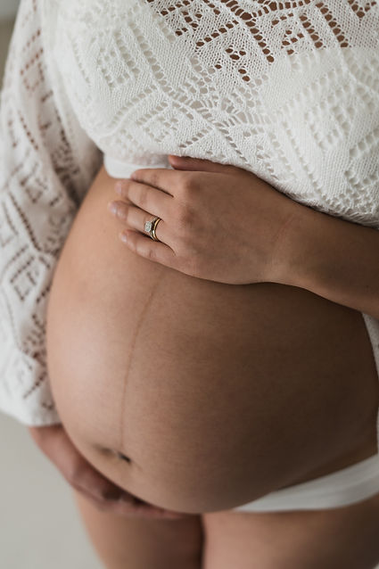 Close-up of a pregnant women's hands resting on her baby bump during a maternity session