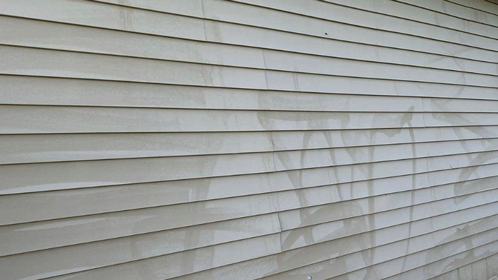 Oxidized vinyl siding with chalky streaks and uneven discoloration on a residential home exterior.