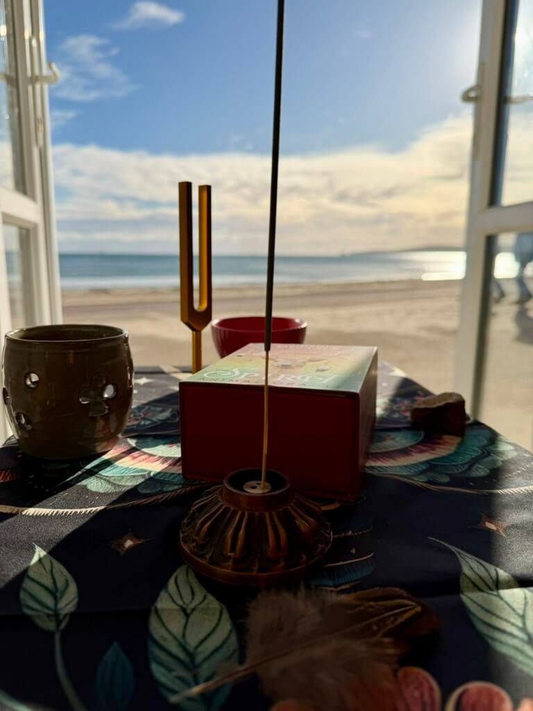 A Shamanic Ceremony set up at Sandbanks beach, including oracle cards, a tuning fork and representations of the elements, prepared for a client's ceremony.
