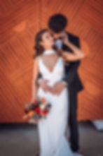 Bride and groom in front of orange, wooden double-doors.