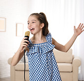 Cute girl singing in microphone at home.