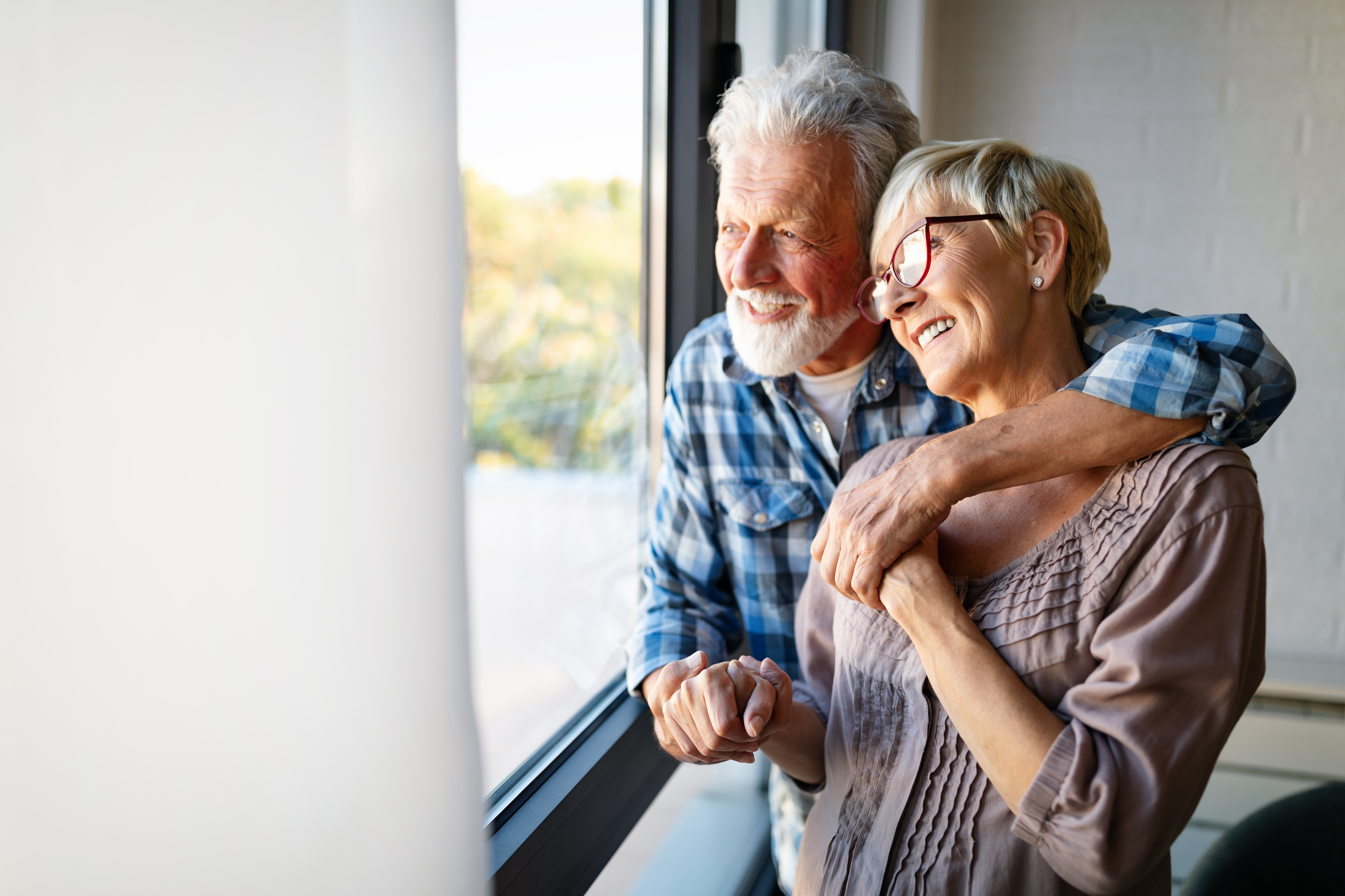 Woma and man hugging while looking out window