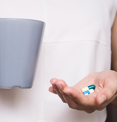 Peson holdig a mug and pills in hand