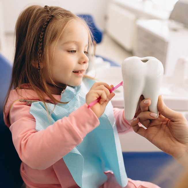 young girl practicing with toothbrush at dentist