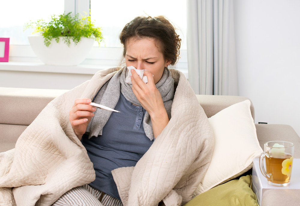 sick woman checking temperature and blowing nose