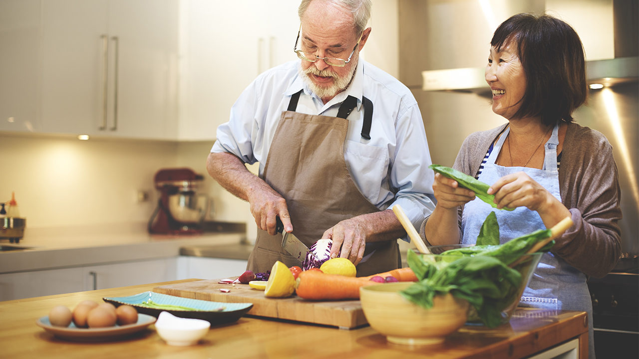 senior couple prepping food in a kitchen