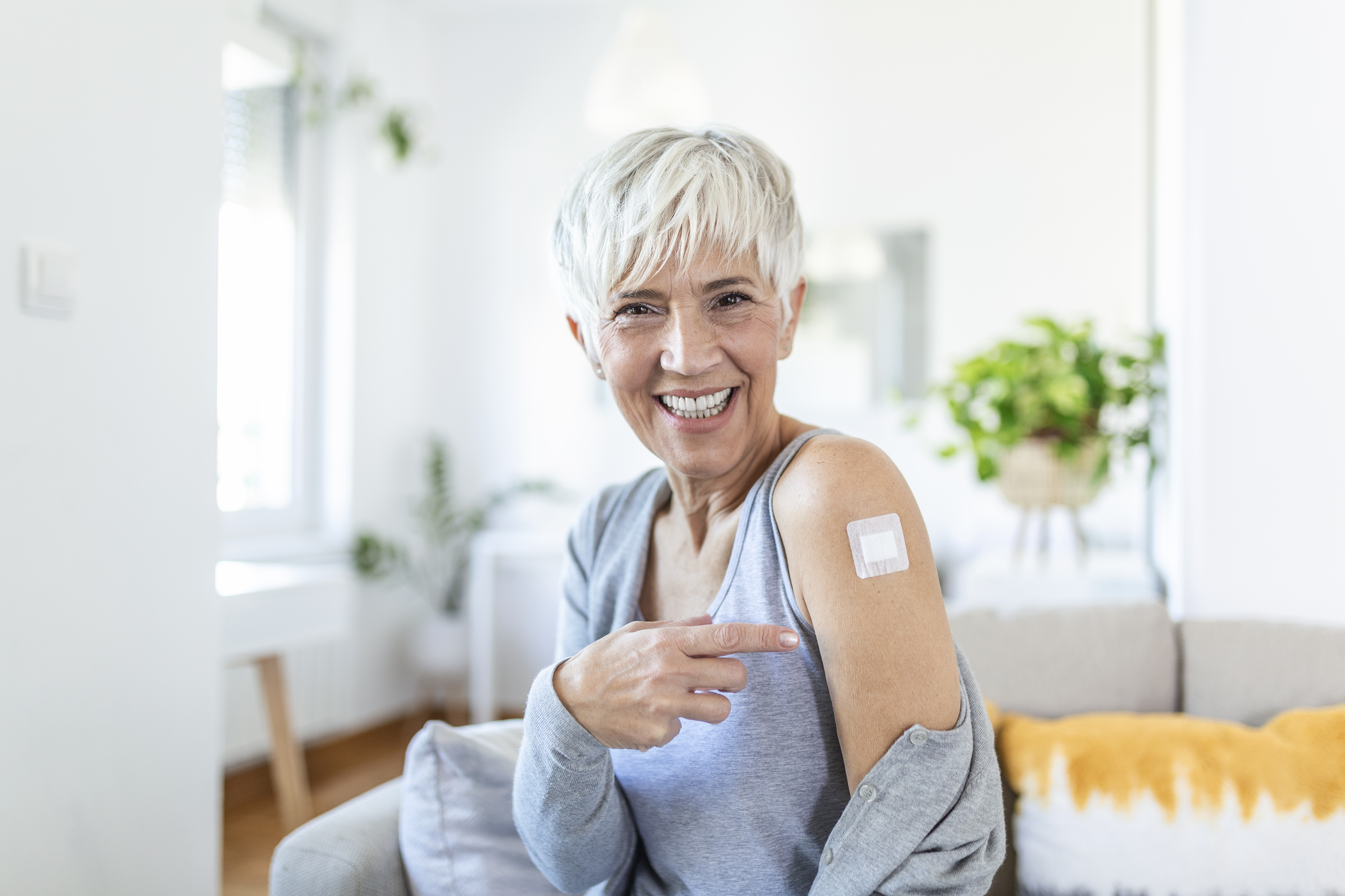 senior woman smiling pointing to bandaid on her arm