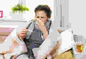 sick woman checking temperature and blowing nose