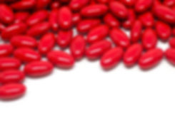 A bunch of bright red pills on a white background