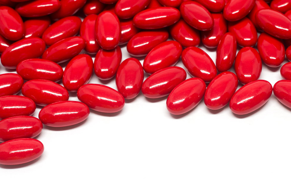A bunch of bright red pills on a white background