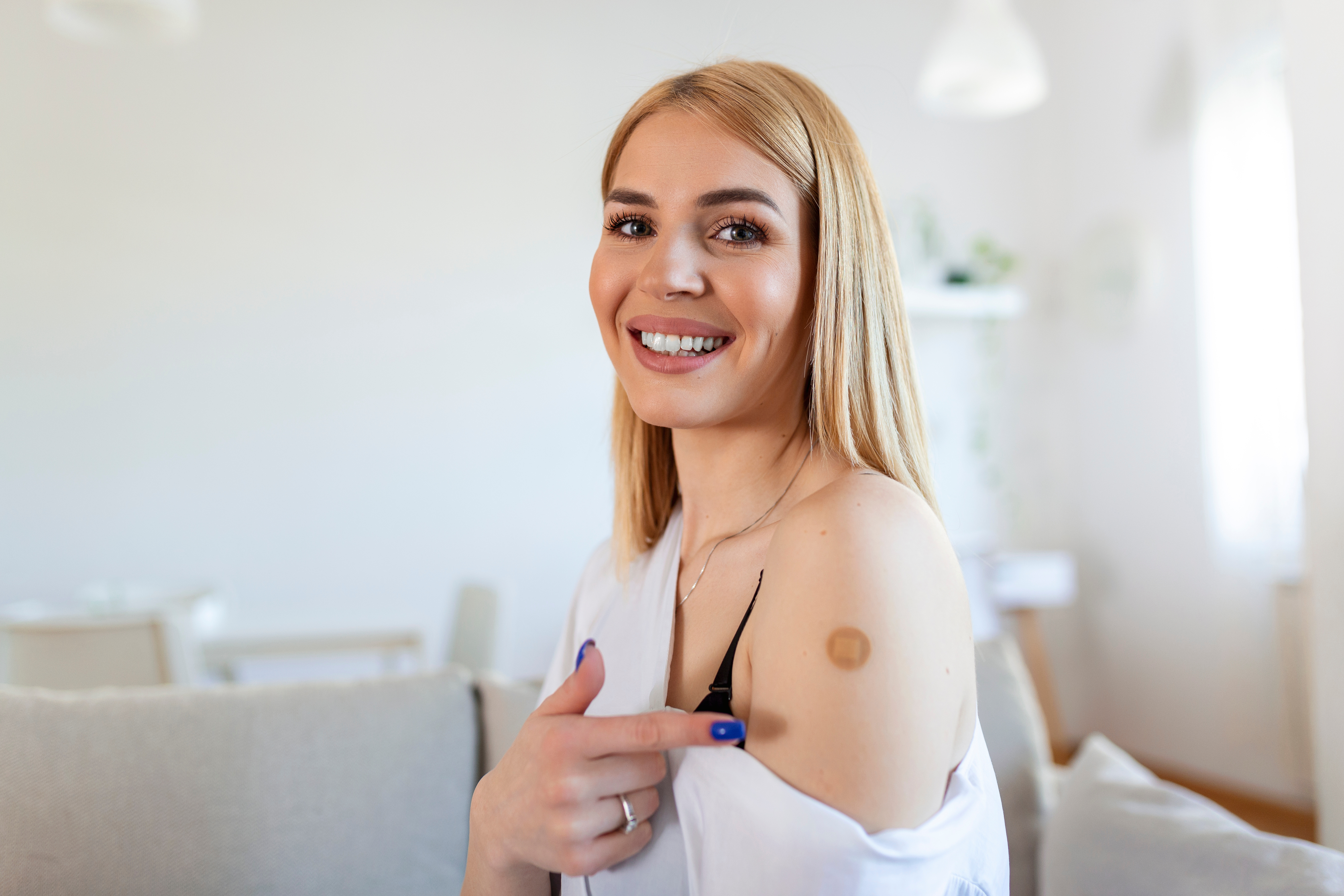 Woman pointing at bandaid on arm after getting vaccines