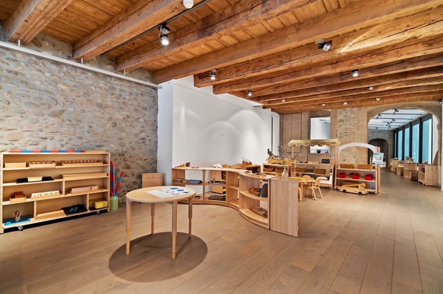 A calm, light‑filled classroom at La Nouvelle Ecole in Geneva’s Old Town, carefully prepared for bilingual French–English learning with Montessori‑inspired materials.