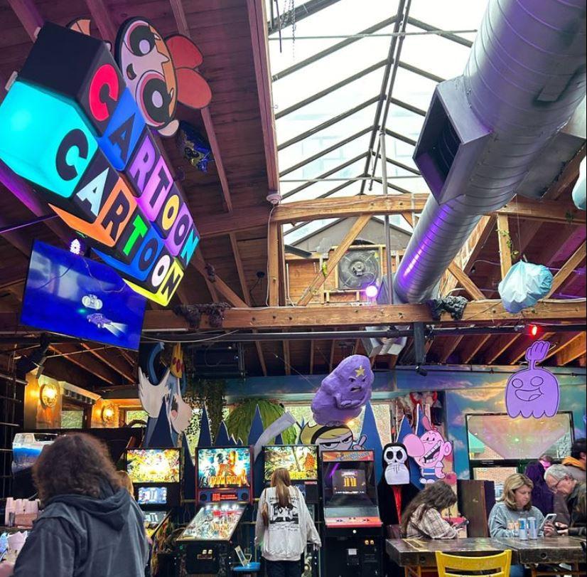 High angle view of a crowded pinball tournament with players focused on machines