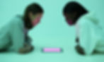 Guy and girl staring down at lit tablet