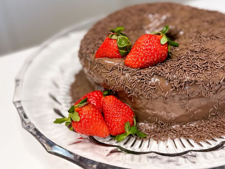 Bolo de chocolate recheado com creme branco, morangos e cobertura de brigadeiro