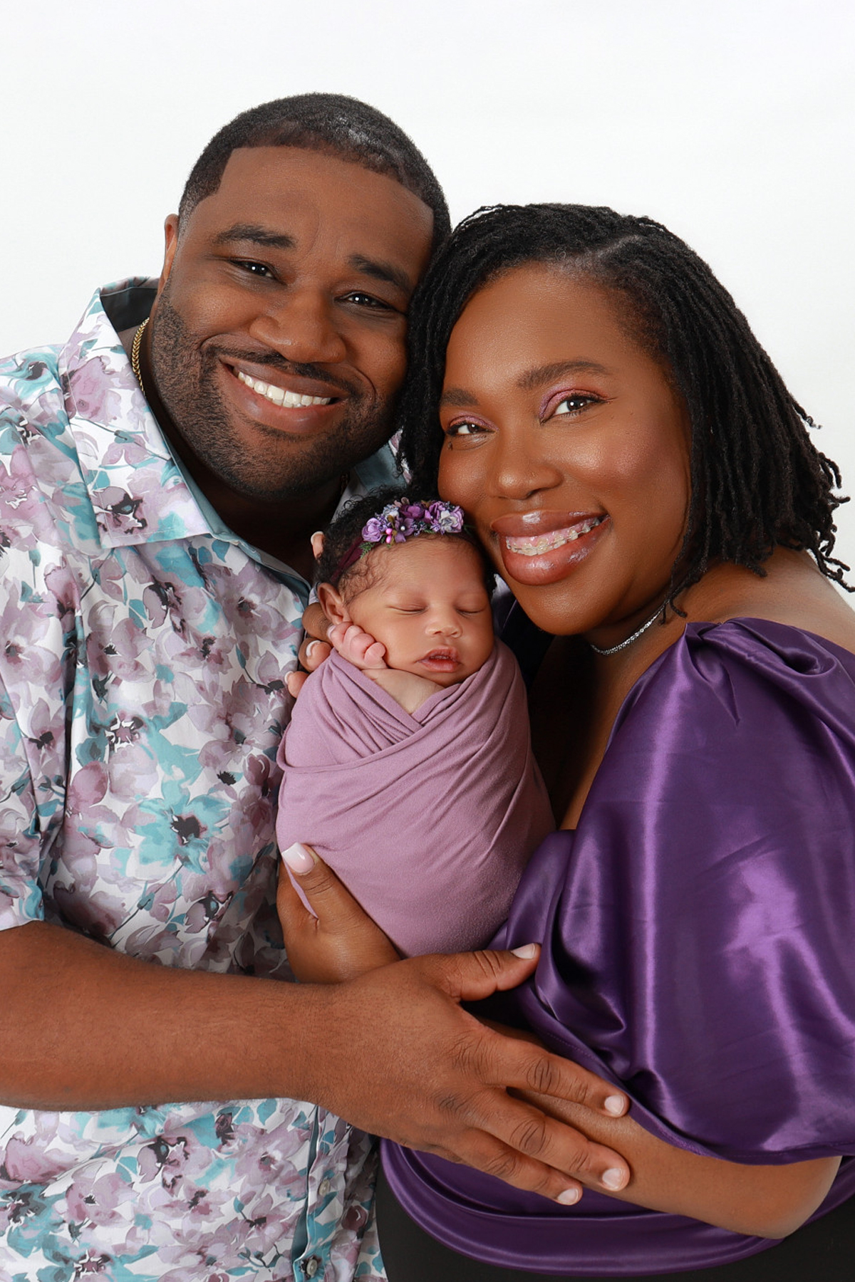 Family holding their newborn and looking at the camera