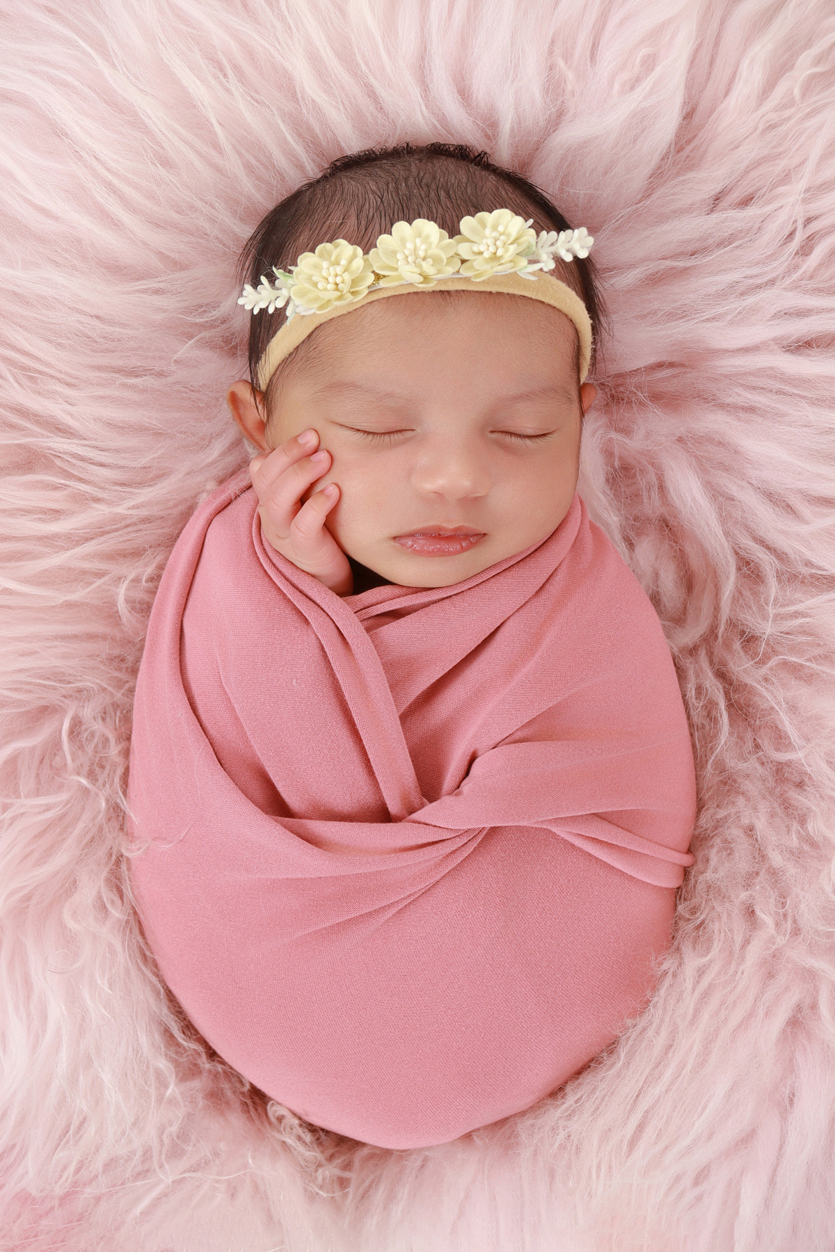 Newborn in pink with hands under chin
