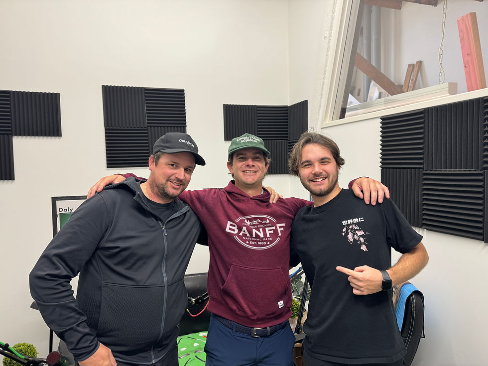 Three people standing together in a recording studio, smiling at the camera; landscape photo