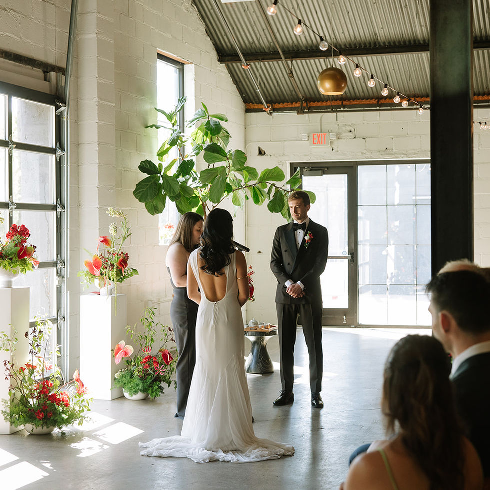 Wedding ceremony in industrial setting with afternoon sunlight, red ikebana-inspired flowers. Venue is Paikka, St. Paul, MN