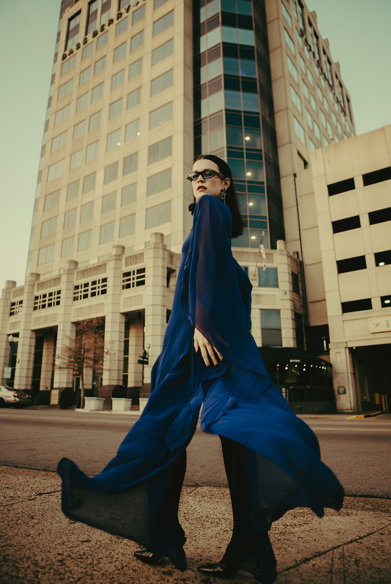 Editorial fashion shot of a model twirling in a blue flowy dress with urban downtown Memphis backdrop.