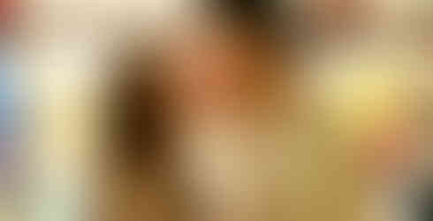 Couple kissing in front of popcorn stand leaning in together in casual outfits during couples carnival photoshoot 