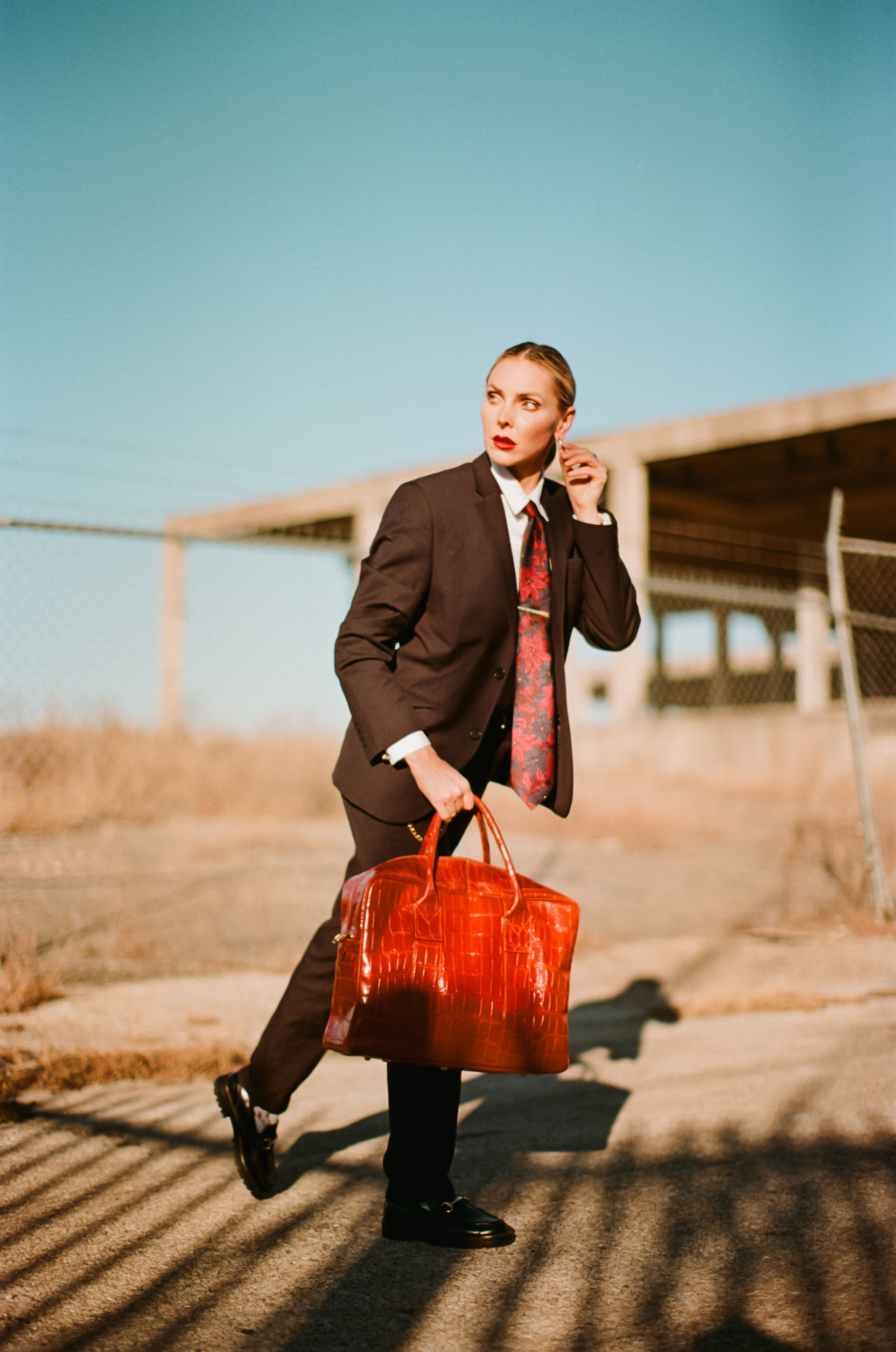 woman holding a purse in a suit posing for a photo during temple texas photoshoot with a temple texas photographer