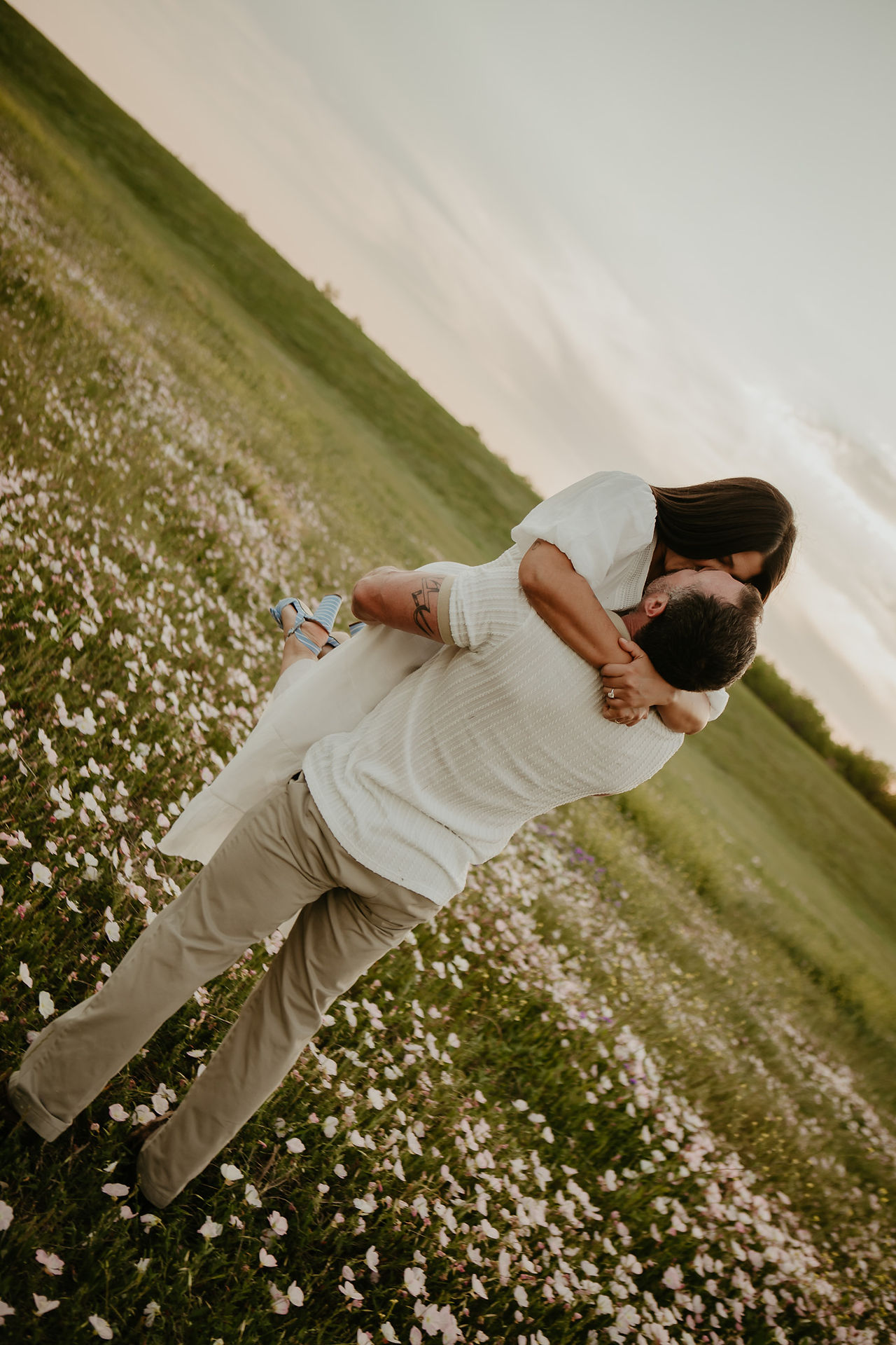 man picking woman up in wildflowers