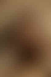 Girl with hands in hair posing for editorial portrait against plain wall