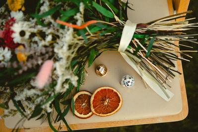 Floral arrangement, rings, and orange slices sit on display; Weddings & Elopements.