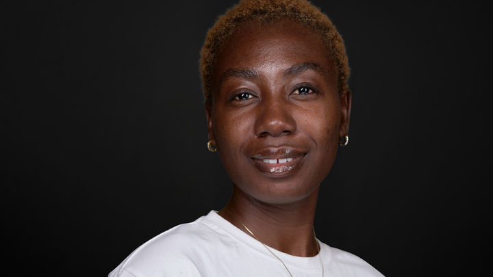 Professional headshot of a confident black woman, wearing a white top against a dark grey background. Captured with expert lighting and sharp focus, ideal for look books, spotlight profiles, LinkedIn, and branding. Photo by North Star Images.