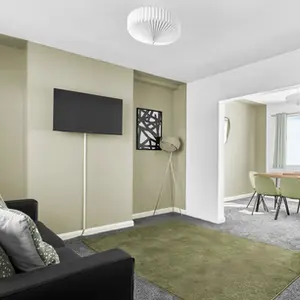 Property Photography North East is a folio of North Star Images
Specialising in Serviced accommodation photography, interior Photography HMO Photography and student accommodation photography Durham
A modern HMO living room featuring two black sofas with decorative cushions, a green area rug, and a television mounted on the wall. A dining area is visible through an open doorway, with a table and chairs near a window. This shows that a a modern HMO photographed by property Photography North East a folio of North Star Images.