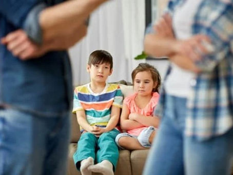 Upset children in view with parents in front and out of focus, clearly having a dispute over the execution of parenting orders.