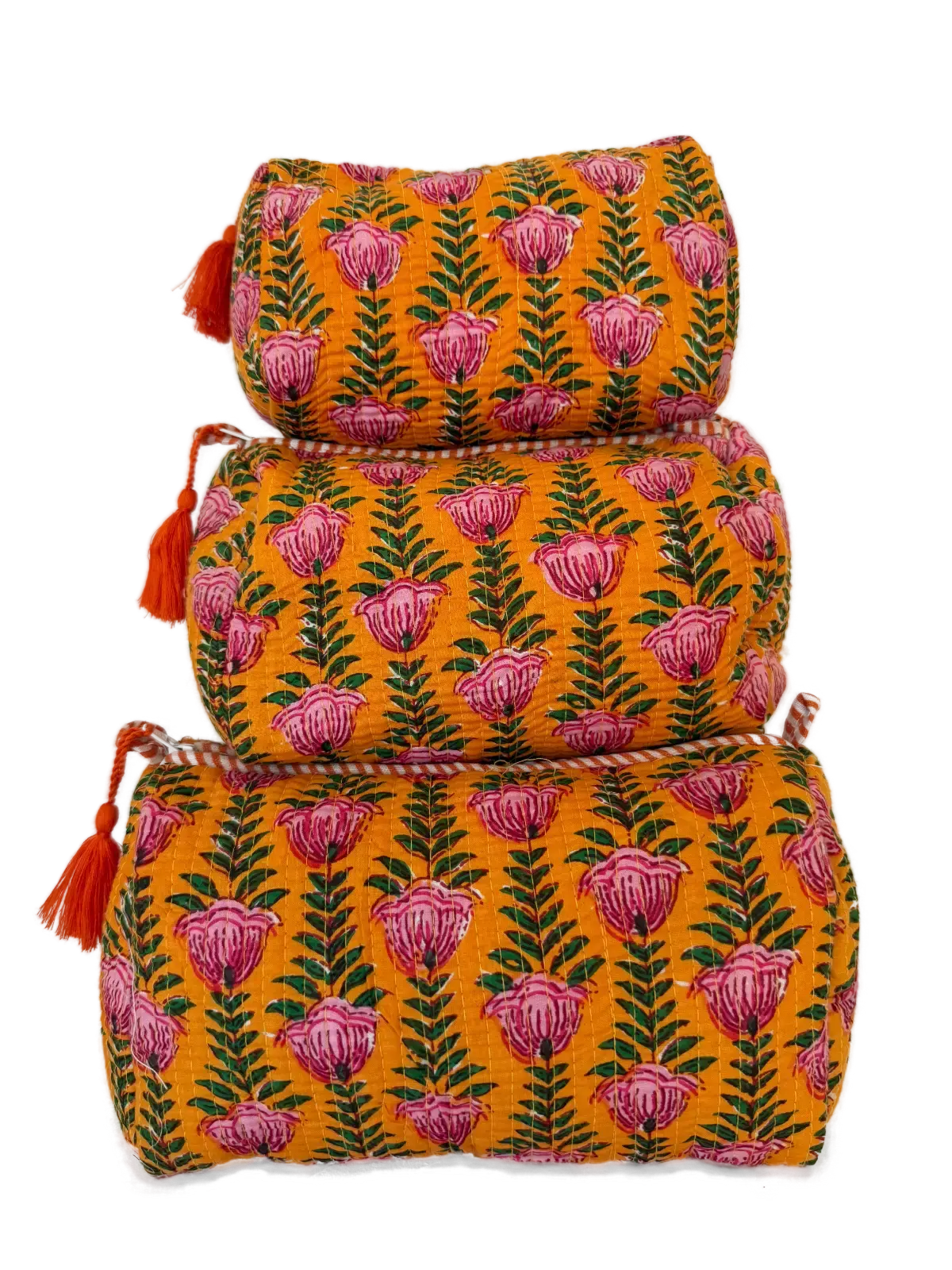 a quilted cotton pouch set in warm saffron tones with pink floral print and tassel detail.