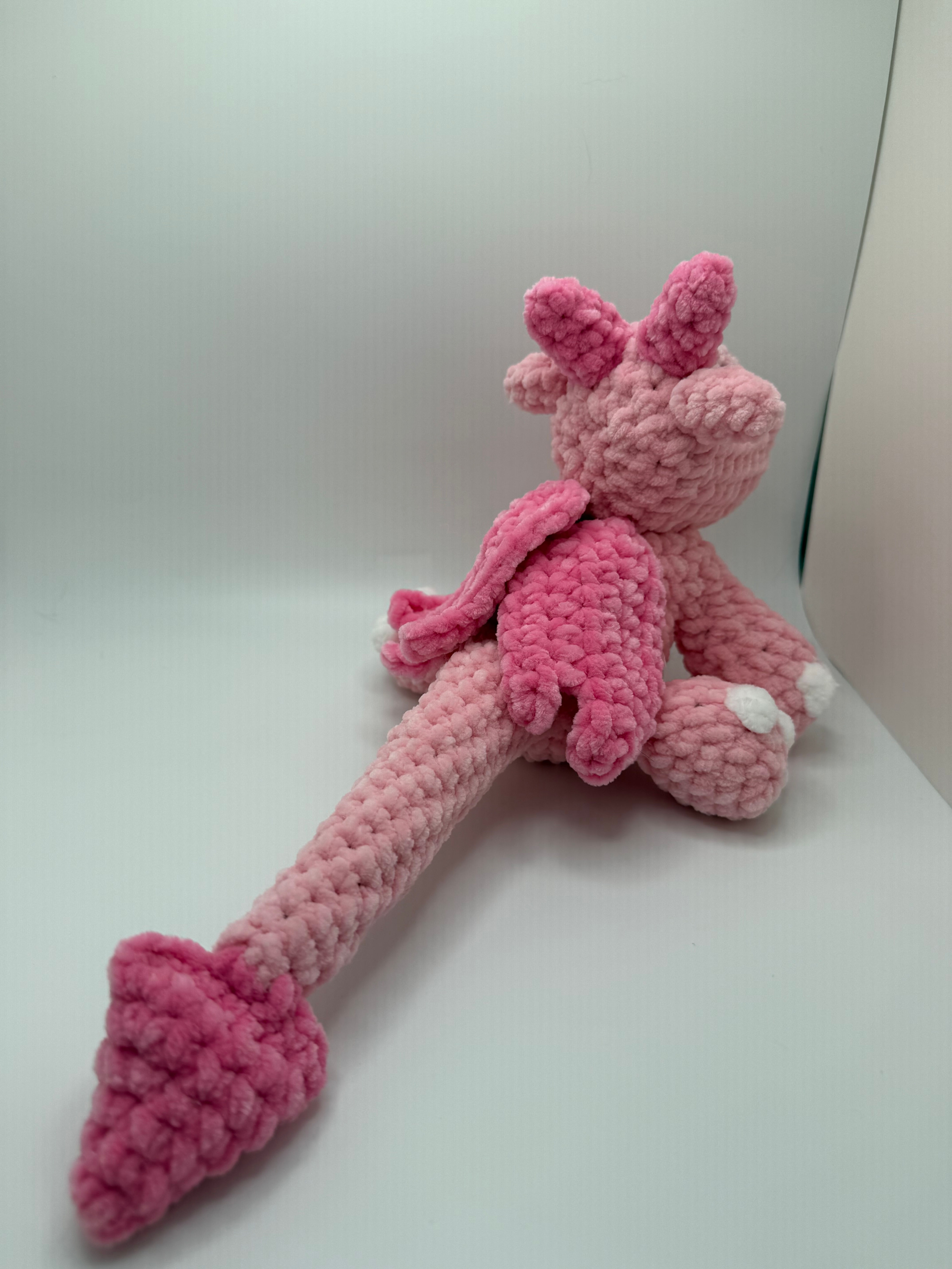Pink amigurumi dragon hatchling with long tail