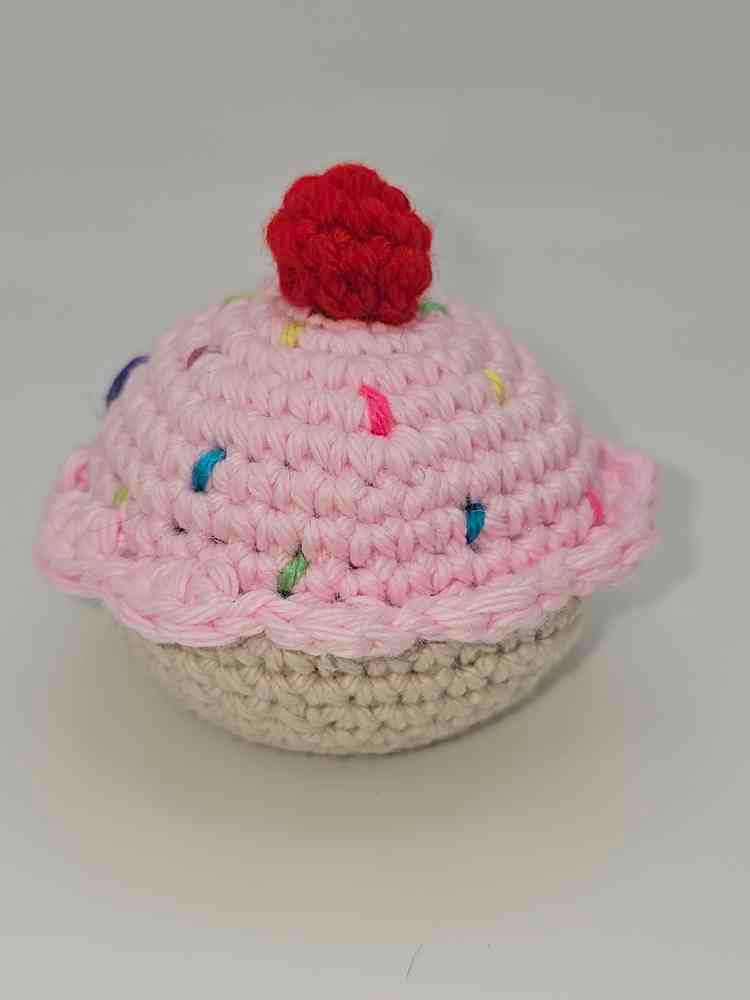Amigurumi cupcake with pink frosting, sprinkles, and cherry