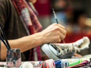 l'artista Maura Petrini dipinge a mano su una scarpa con colori e pennelli 