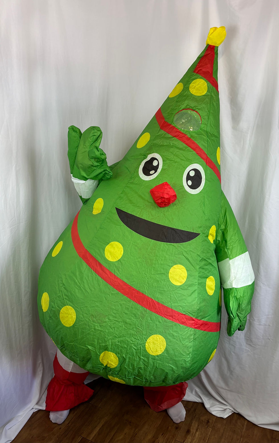 Adult wearing an inflated green Christmas tree costume decorated with printed ornaments and a star