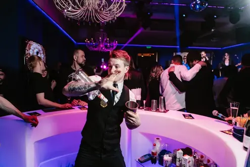 Flair bartender performing bottle tricks while preparing cocktails at a lively Las Vegas nightlife event. Interactive cocktail entertainment keeps guests engaged, enhances the bar experience, and adds energy to corporate parties, VIP receptions, casino events, and private celebrations.