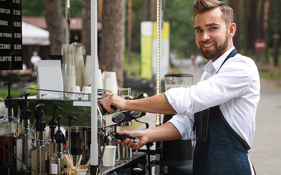 Professional event barista in Los Angeles preparing espresso drinks at a mobile coffee station during an outdoor event, representing trained event bar staff specializing in barista service. The image highlights hands-on coffee preparation, espresso machine operation, organized syrups and cups, and confident guest-facing service. Ideal for clients hiring event bar staff in Los Angeles who need skilled baristas to run mobile coffee bars, serve espresso and specialty beverages, manage high-volume service, and maintain smooth guest flow at corporate events, brand activations, and private gatherings.