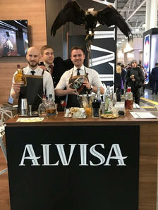 Brand specialist for trade shows in Los Angeles working a premium spirits booth during a large industry expo, presenting branded cocktails and product samples to attendees. Professional brand ambassadors stand behind a custom trade show counter, showcasing bottles, glassware, and tasting setups while engaging visitors with brand education and product demonstrations. Ideal example of Los Angeles trade show staff, brand specialists, and promotional teams delivering interactive brand experiences at conventions, expos, and corporate trade shows in Los Angeles.
