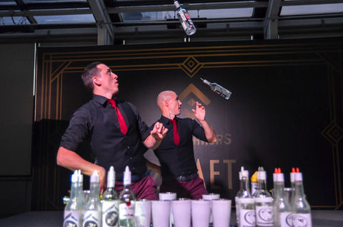 Two flair bartenders in Los Angeles perform a synchronized bottle-flipping show behind the bar during a luxury corporate event. Flair bartending entertainment combines craft cocktails, interactive guest engagement, premium beverage service, and live bar performances for cocktail receptions, gala dinners, company parties, VIP events, and private celebrations.