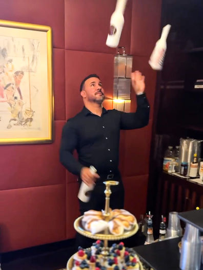 An experienced flair bartender in Los Angeles performs an interactive bottle-flipping show while preparing cocktails behind the bar at a luxury private event. Live flair bartending entertainment combines craft cocktails, premium beverage service, guest engagement, and bar performance for corporate events, cocktail receptions, galas, and VIP parties.