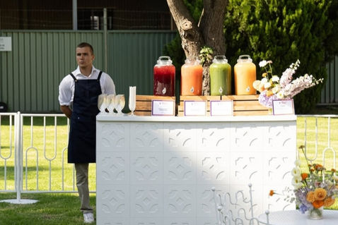 Buffet service attendant supporting a catered outdoor event in Las Vegas. Hospitality staff member managing beverage station presentation, guest assistance, food service coordination, and buffet operations for private parties, wedding receptions, corporate gatherings, and networking events.