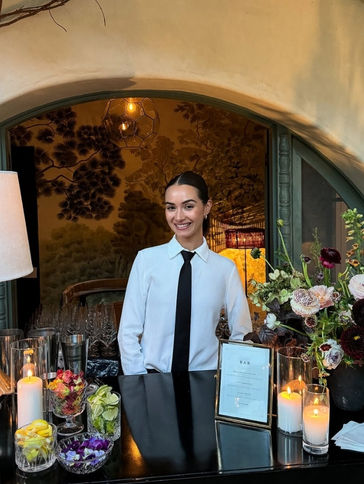 Professional Los Angeles bartender welcoming guests at a private residence event bar. Positioned at a custom beverage station with floral décor and premium glassware, the bartender supports cocktail hour hospitality for intimate celebrations, dinner parties, and luxury home receptions.