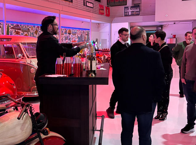 Bartender operating a mobile full bar setup during a corporate event in San Francisco, serving guests in a branded indoor venue with high foot traffic and social interaction. The image highlights a bartender preparing drinks while engaging attendees at a standing bar station, with bottles, mixers, and bar tools arranged for quick access. Ideal for corporate mixers, product launches, and networking events across the Bay Area where efficient drink service, guest engagement, and structured bar flow are essential.