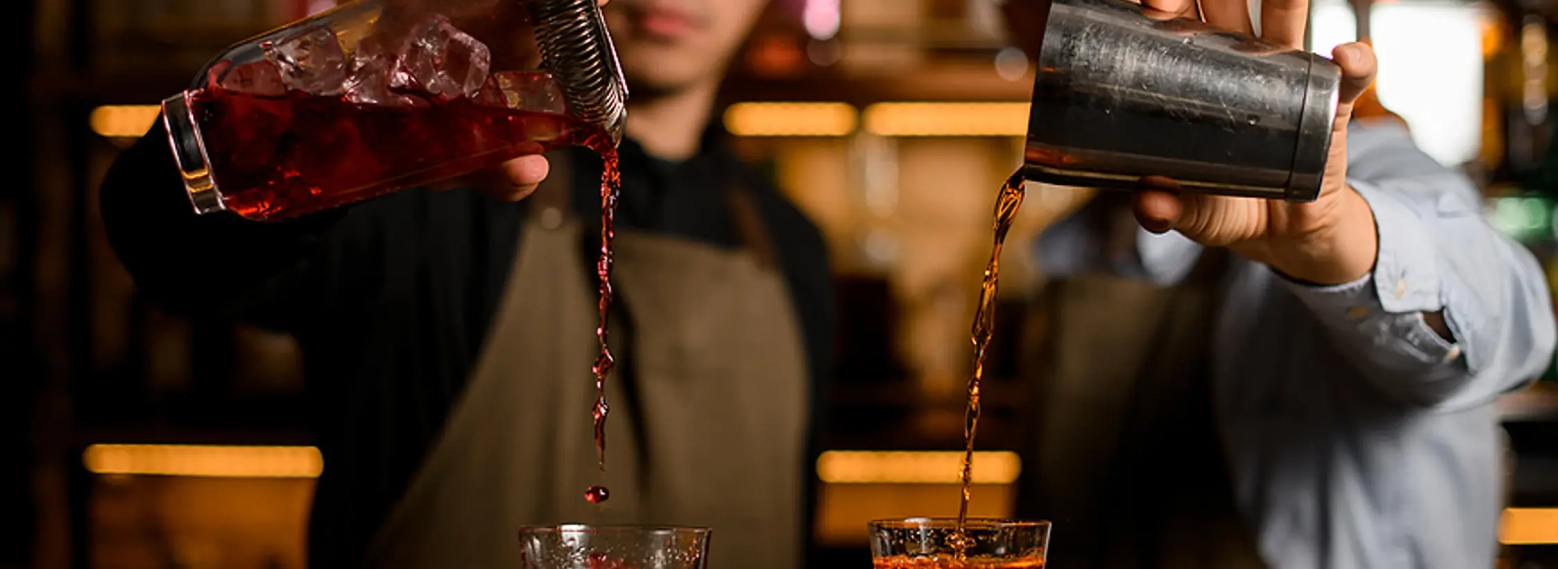 Bartenders in Los Angeles preparing cocktails at a high-volume event bar, pouring drinks with cocktail shakers — visual of professional mixology service for private parties, weddings, and corporate events.