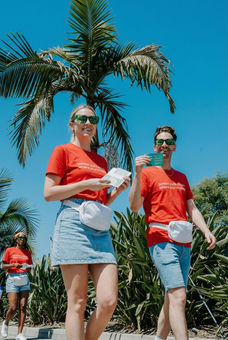 Street team promo staff in Los Angeles distributing flyers and product samples during an outdoor brand activation ahead of FIFA World Cup 2026. Promotional staff in branded t-shirts engage with pedestrians in high-traffic areas, supporting fan engagement, guerrilla marketing, and experiential campaigns. Event staffing for FIFA 2026 Los Angeles including street teams, brand ambassadors, and promo models delivering high-volume outreach and direct-to-consumer interaction.