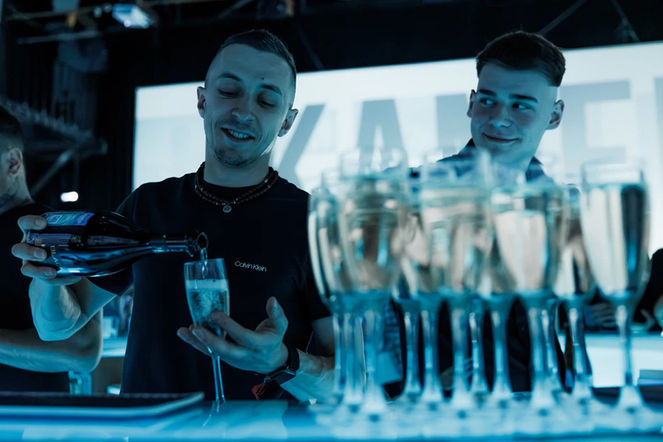 Professional event bar staff in Los Angeles pouring champagne behind a modern event bar, representing experienced bartenders, mixologists, and baristas working corporate events, brand activations, nightlife events, and upscale private parties. The image highlights organized glassware, champagne service, and coordinated bar operations in a high-energy venue. Ideal for clients hiring event bar staff in Los Angeles who need reliable bartenders, skilled mixologists, and professional baristas capable of managing high-volume beverage service, premium drink presentation, and smooth guest flow in fast-paced event environments.